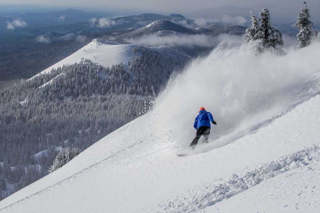 MtBachelor_3_15_23-15-medium (1) A snowboarder carves through deep powder on a snowy mountain slope in Central Oregon.