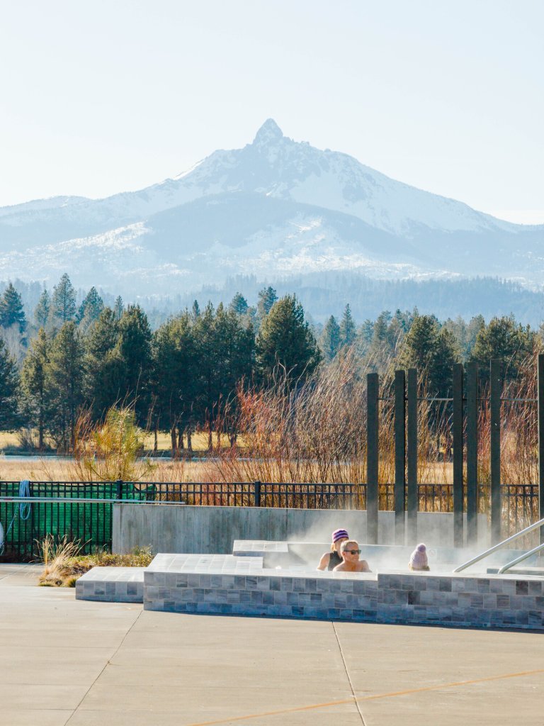 2024-medium People relaxing in a steaming outdoor hot tub with a snow-capped mountain backdrop in Central Oregon.