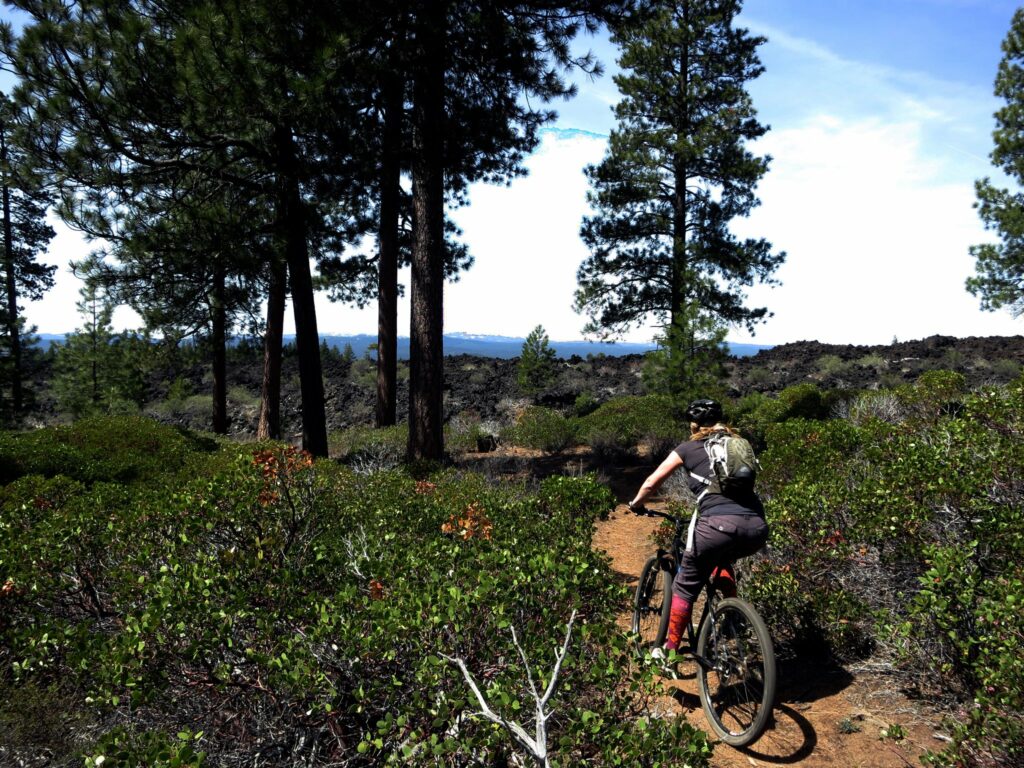 A woman rides a mountain bike through lava fields and trees near Bend, Oregon.