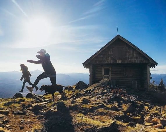 A group of hikers enjoying a scenic mountain view near a rustic cabin in Central Oregon.