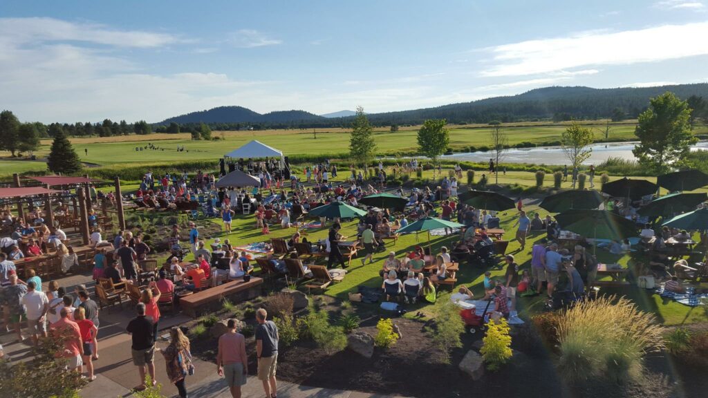 A lively outdoor gathering with people enjoying a sunny day, surrounded by nature in Central Oregon.