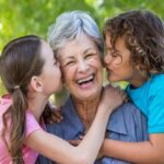 Two kids kissing their grandmother