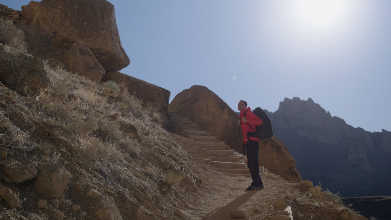 Man in red jacket stares up at Smith Rock in the state park in Terrebonne, Oregon.