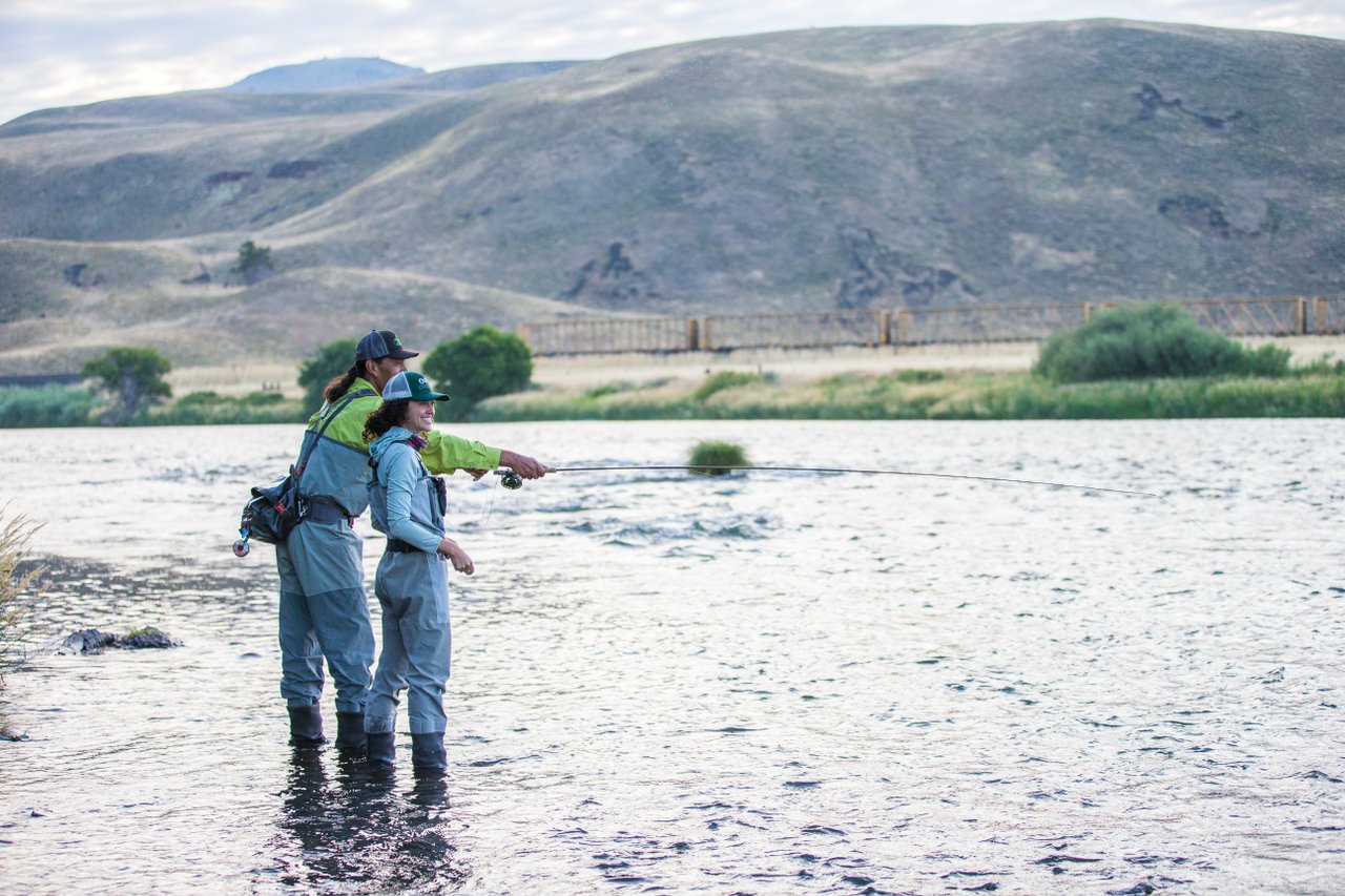 an from Warm Springs guides woman in fly fishing on a river there.