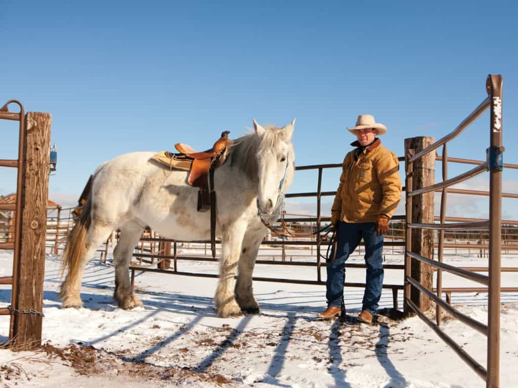 a cowboy standing with his horse at Sunriver Stables