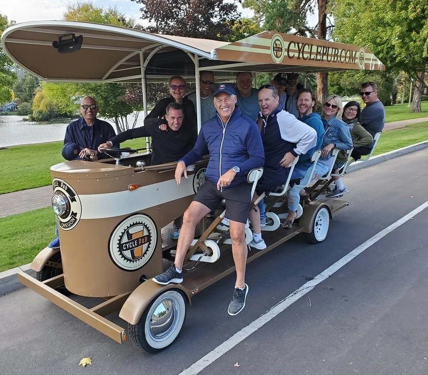 A group peddling down the street while on a cycle pub tour.