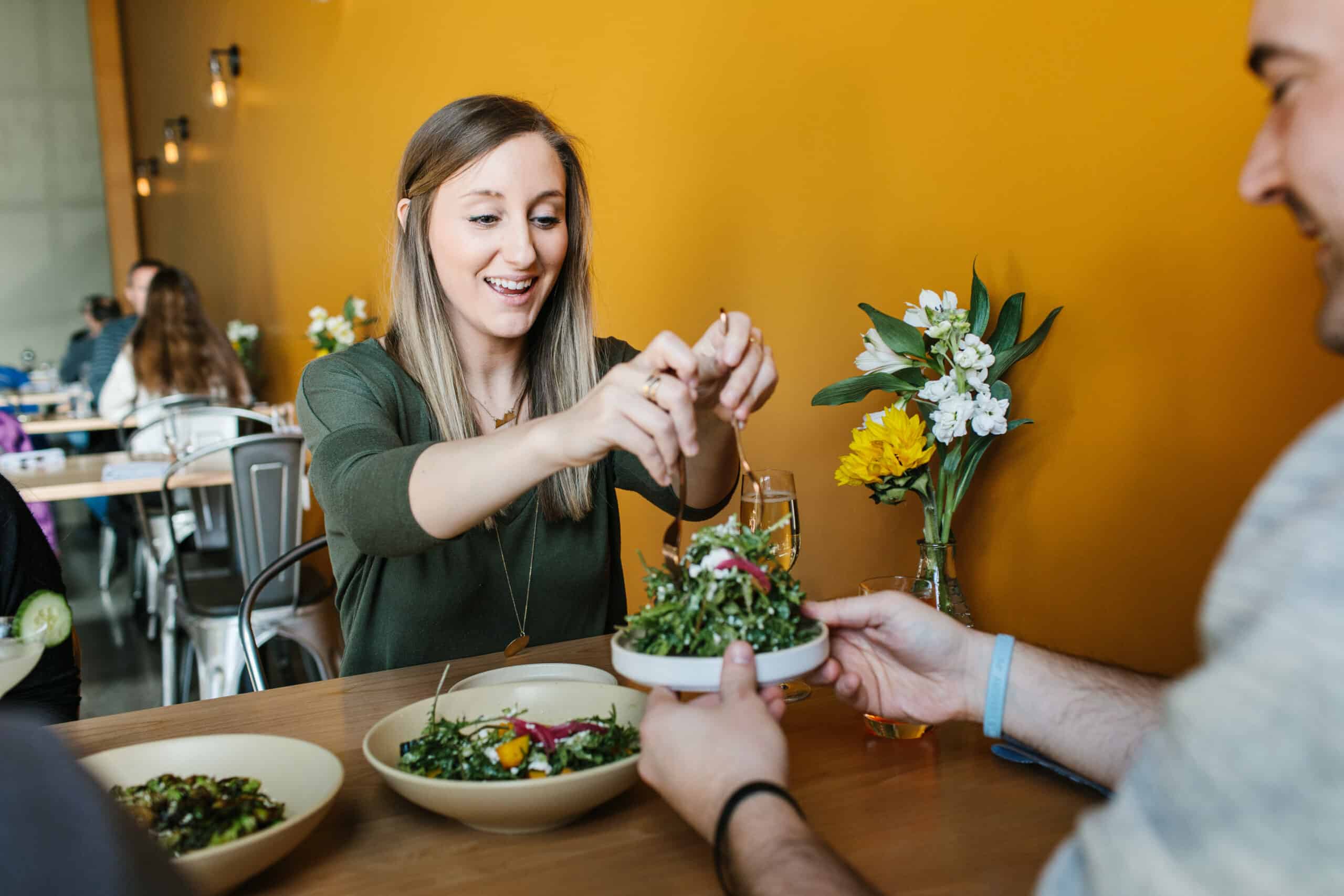 a gal serving up salad at a table inside