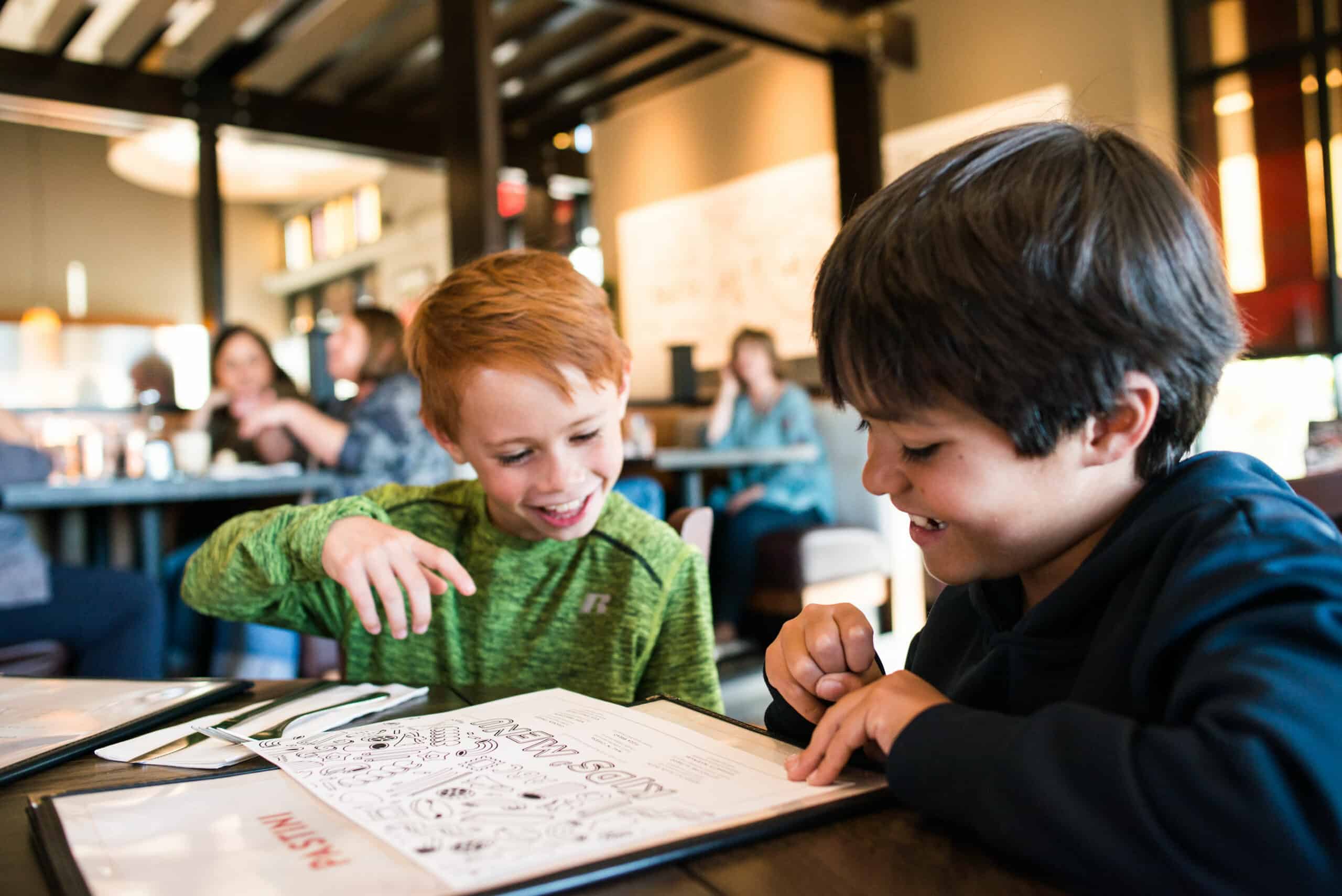 the young boys sitting, looking at a menu at Pastini restaurant