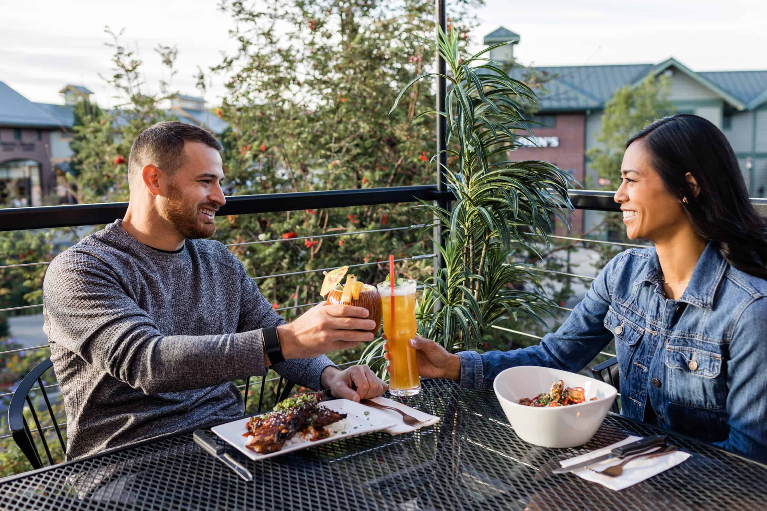 a couple sitting down to a meal and cocktails outside