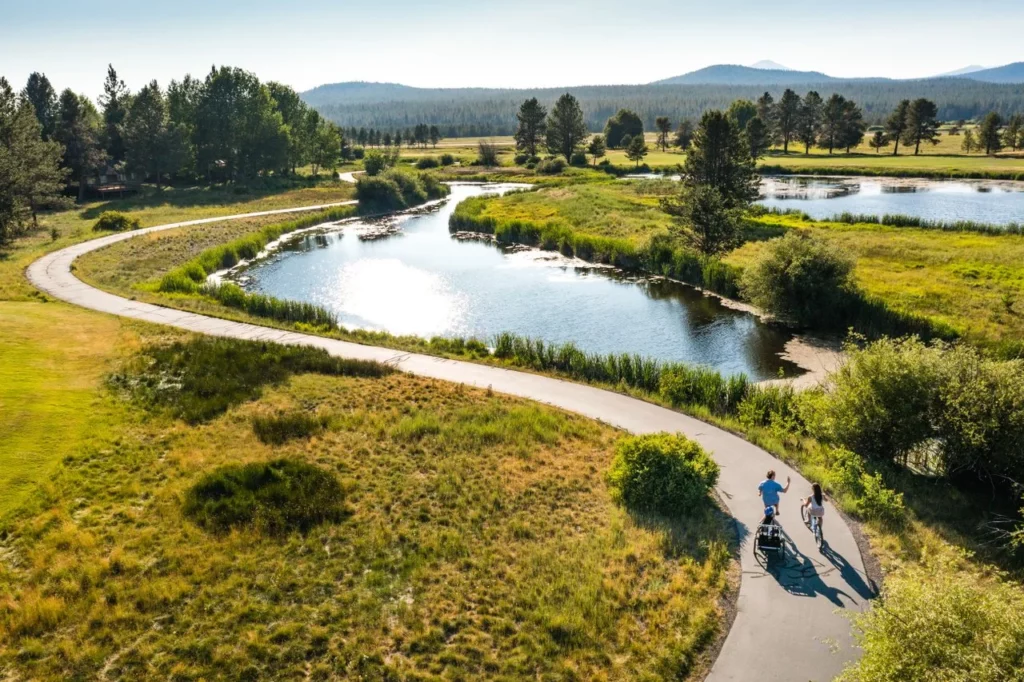 Two people bike down a trail next to a river. 