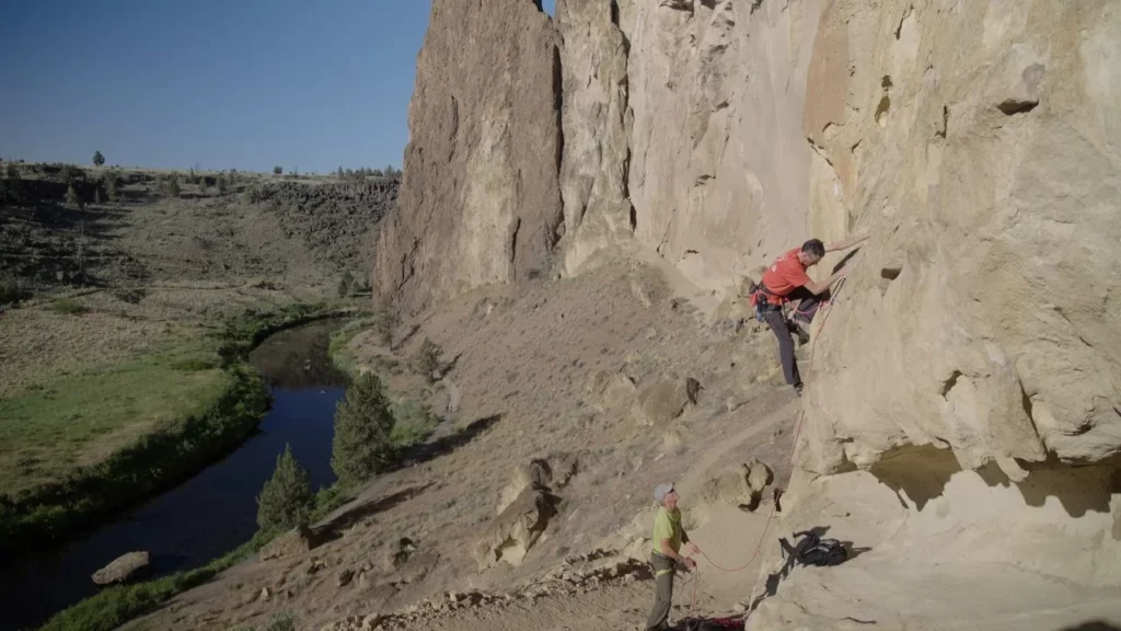 A guy rock climbs at Smith Rock State Park.