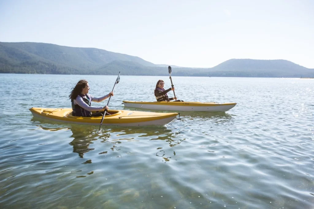 Two people kayak on a lake.