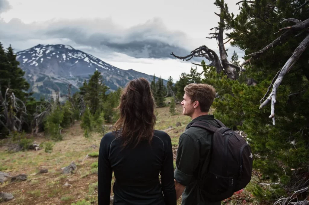 Two people look at Mt. Bachelor while on a hike. 