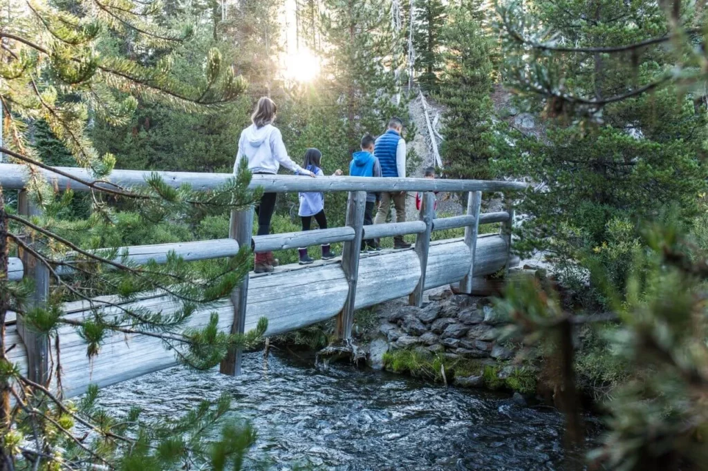 A family crosses a bridge while on a hike.