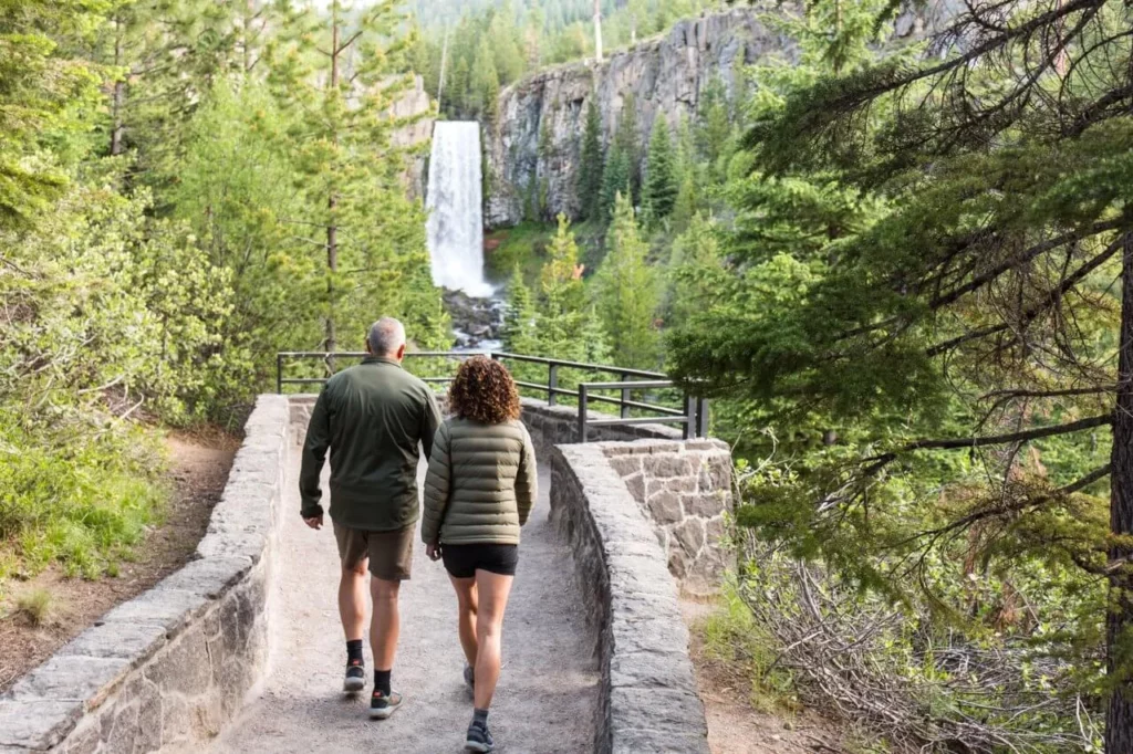 a couple walking toward a Tumalo Falls, a waterfall viewpoint