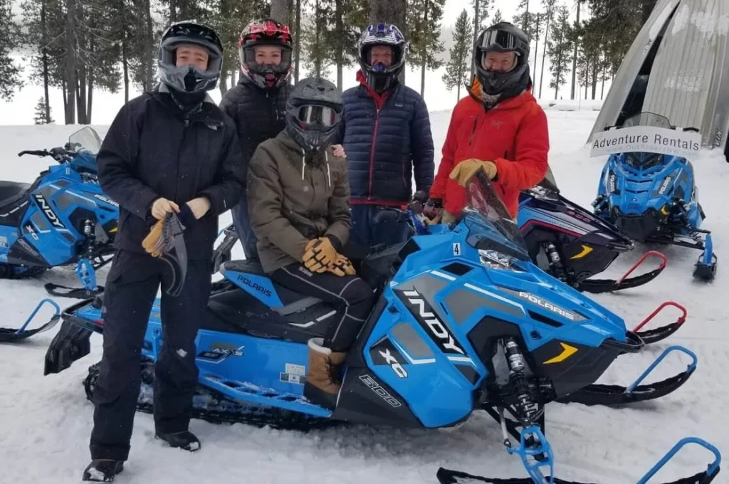 A group poses by a snowmobile. 
