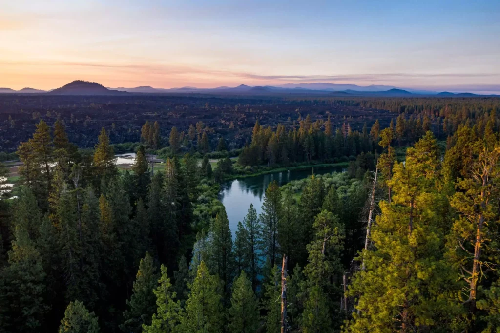 A view of mountain peaks and the Deschutes river flowing through the forests