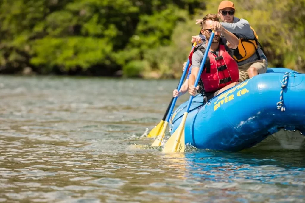 People in a raft paddle.