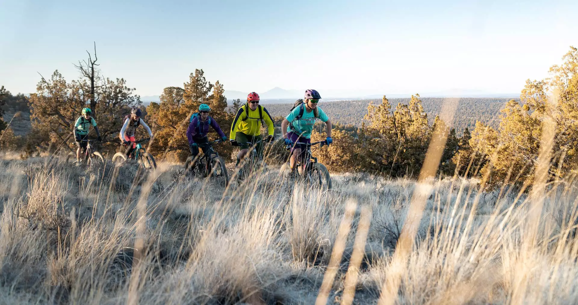 A group of people mountain bike on top of a ridge line.