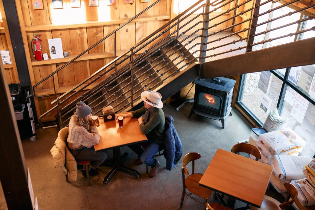 A cozy indoor scene featuring a couple seated at a table, enjoying a drink in a rustic setting in Central Oregon.