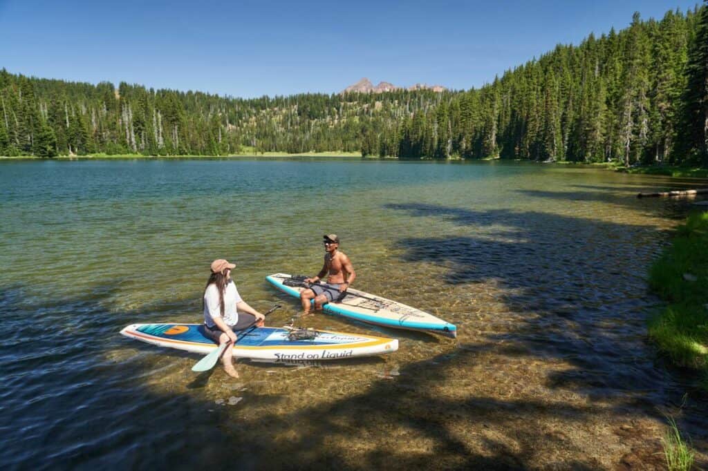 Two people hang out on a stand up paddle board in central oregon. 