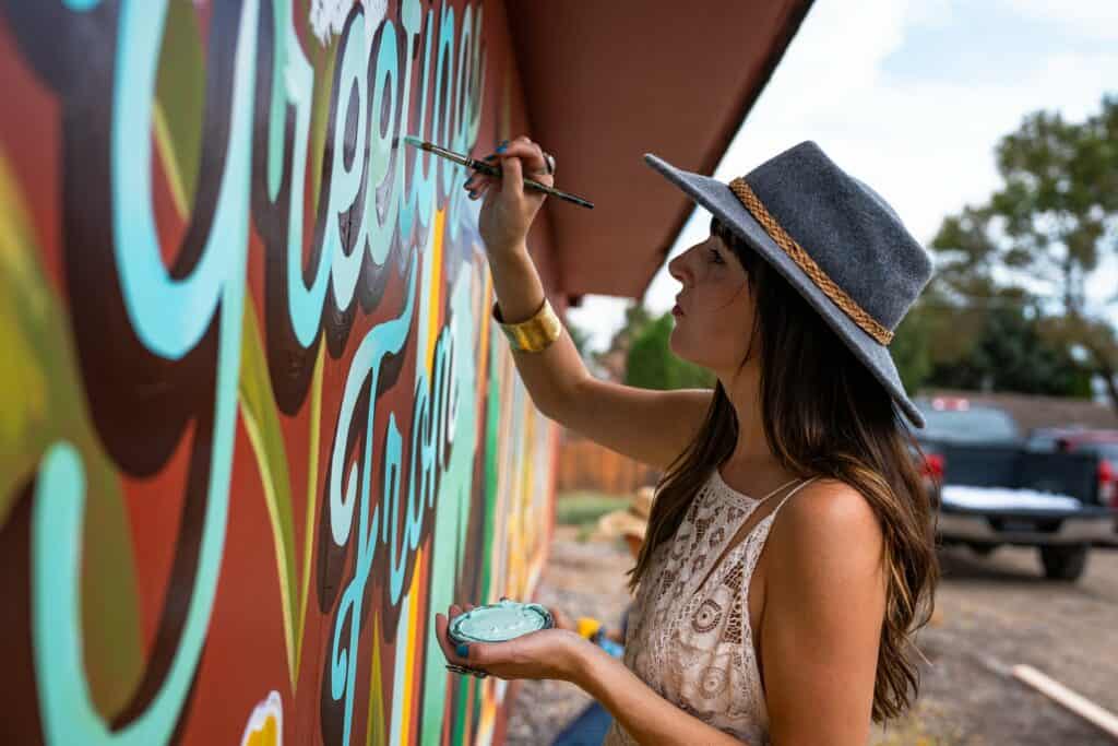Katie Daisy and Karen Eland painting the “Greetings from Madras” mural
