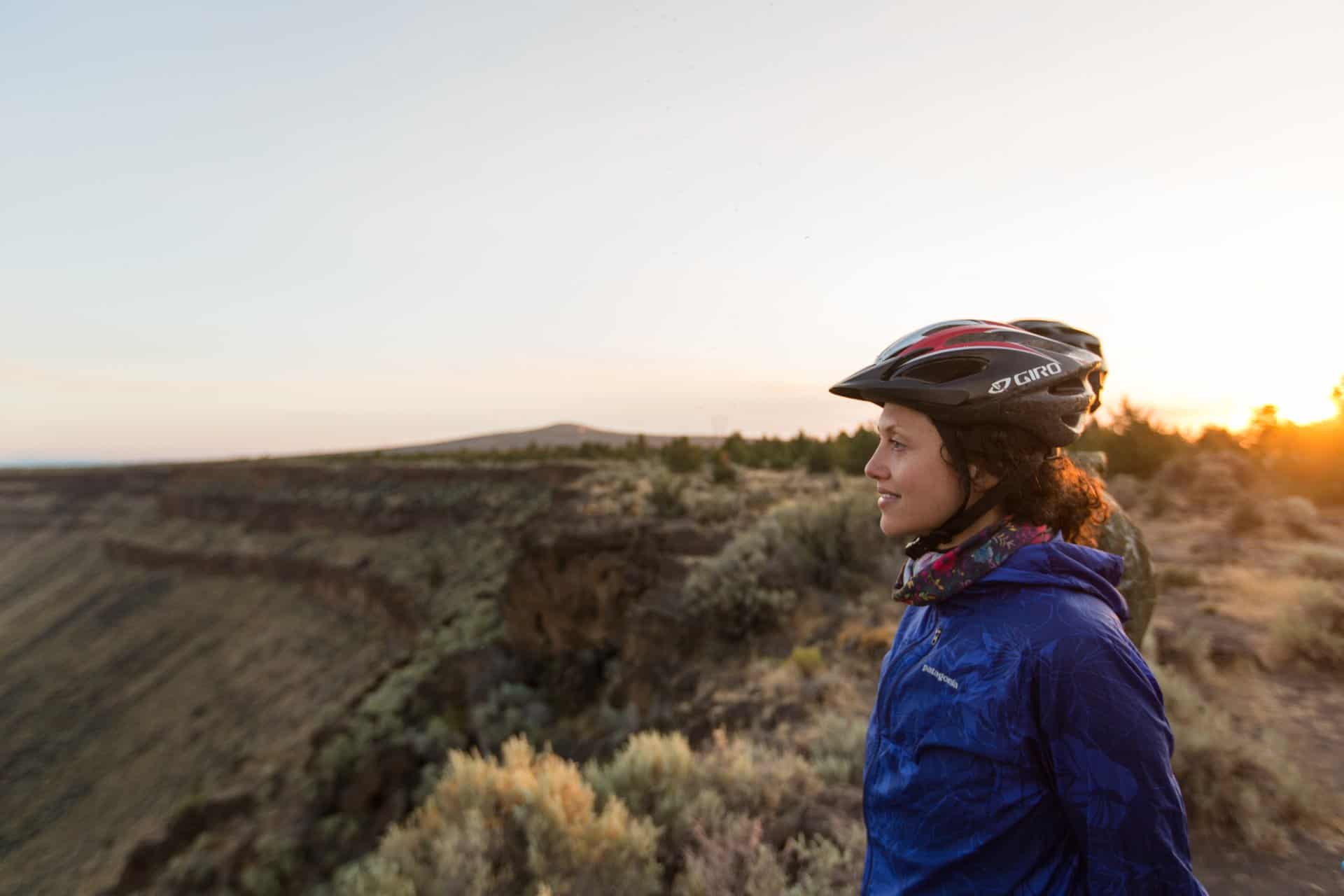 A woman in a bike helmet looks out over a view