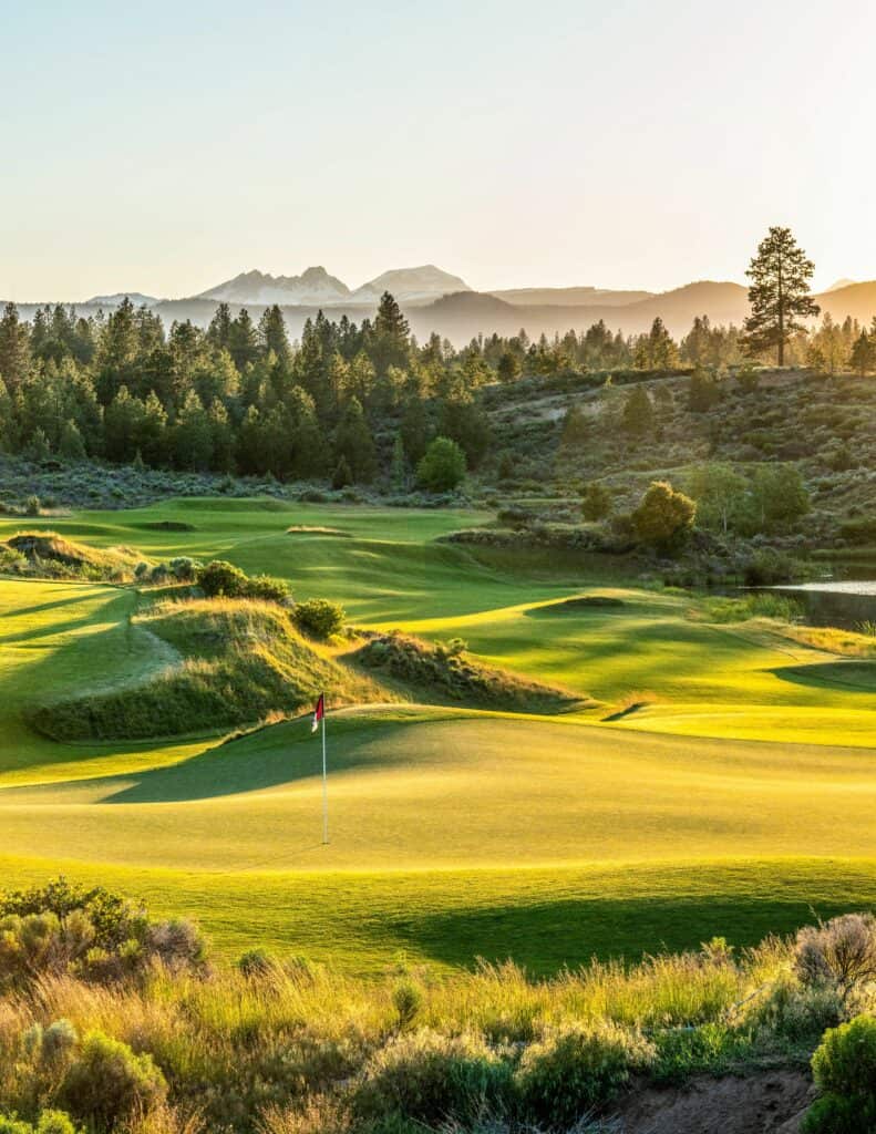 A serene golf course at sunset, with lush greens and a distant mountain range in Central Oregon.