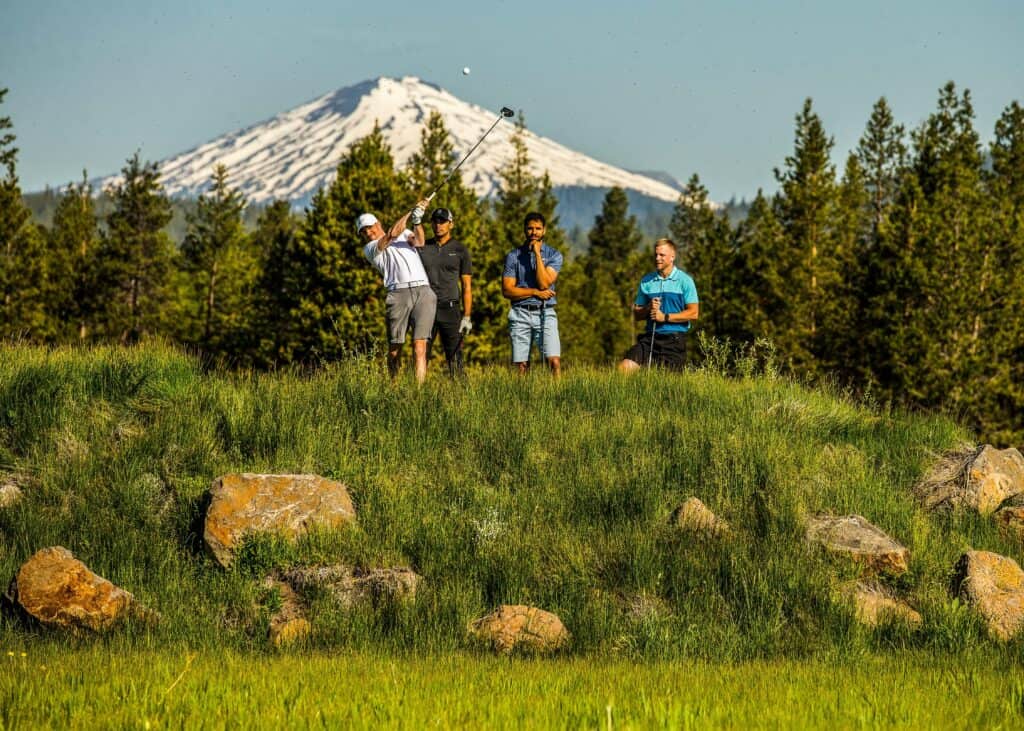 Golfers on a lush green field with a majestic mountain in the background in Central Oregon.