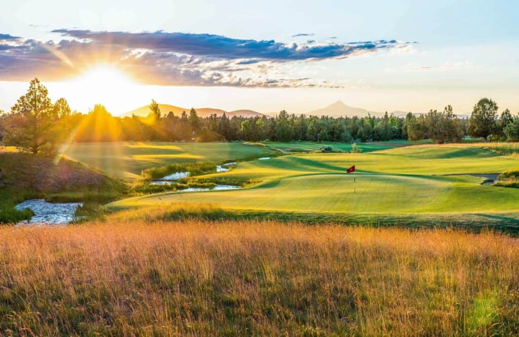 A serene golf course at sunrise, with a red flag on a green tee in Central Oregon.
