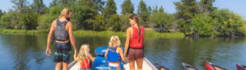 A family preparing to paddle the Little Deschutes River in Sunriver, Oregon.