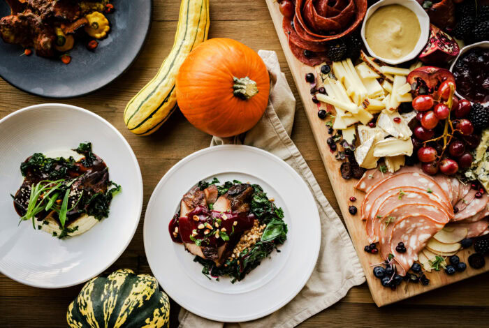 A feast of autumnal dishes, including a roasted pumpkin, a charcuterie board, and a plate of meat and greens in Central Oregon.