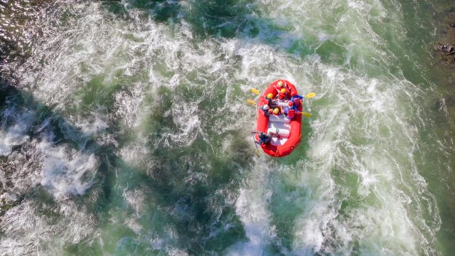 Adventurers navigate whitewater rapids in a raft, surrounded by lush greenery in Central Oregon.