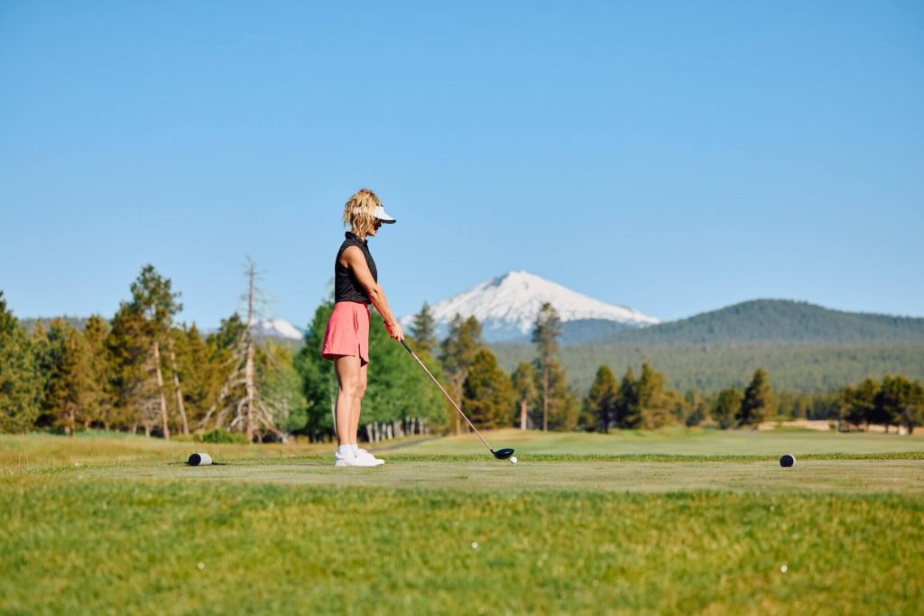 Woman golfing, with Mt. Bachelor in the background, in Sunriver, Oregon