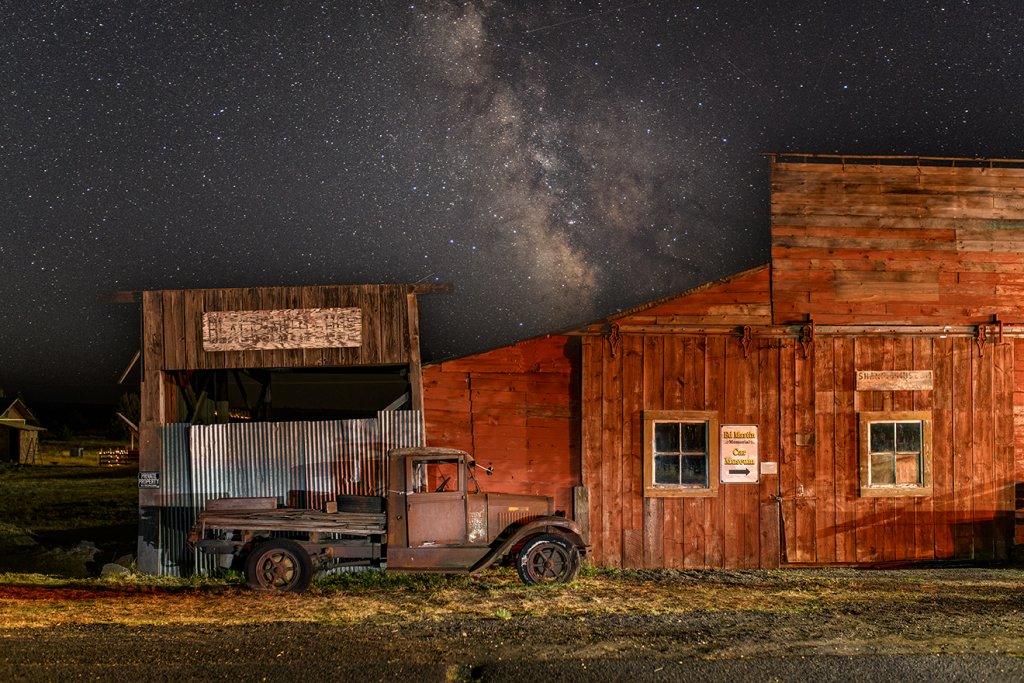 A vintage truck parked beside a rustic barn under a starry night sky in Central Oregon.