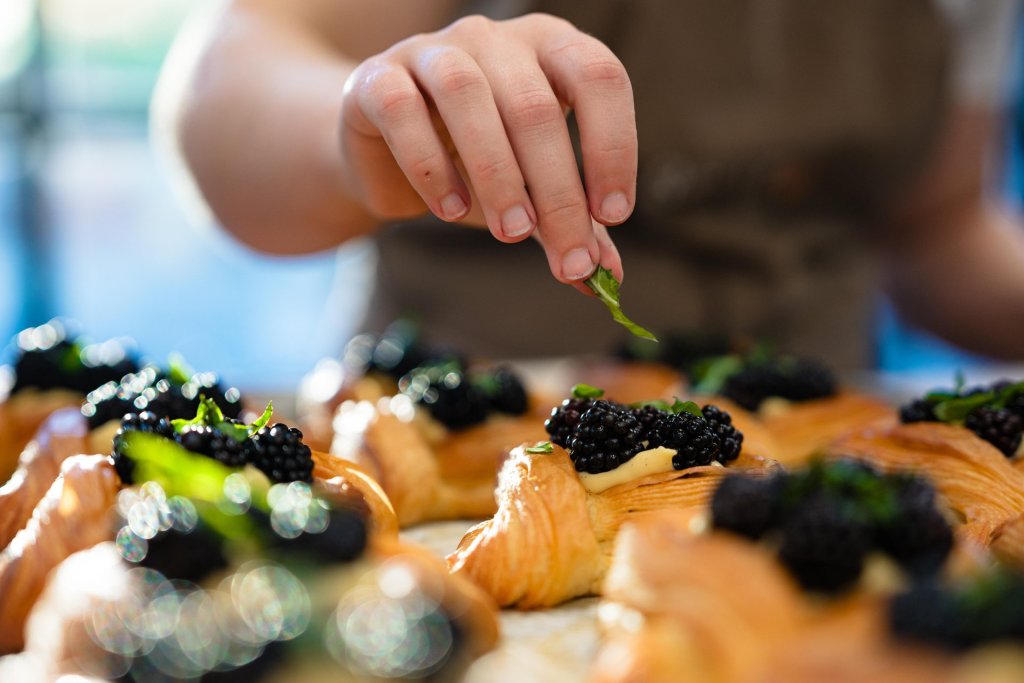 A baker carefully garnishes pastries with fresh berries and herbs in Central Oregon.