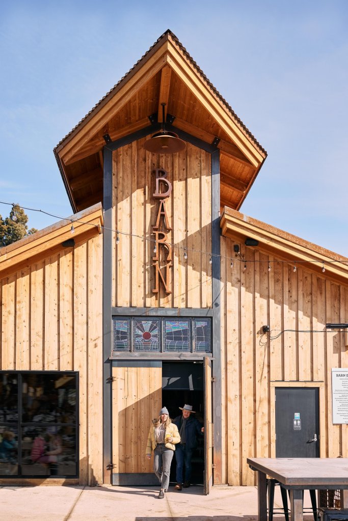 A woman walks towards a rustic wooden barn with a sign reading 'Barn' on its side in Central Oregon.