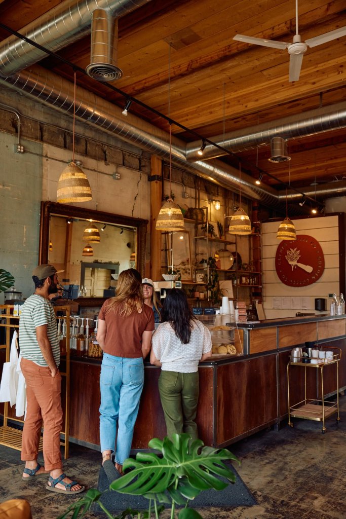 A cozy coffee shop with exposed brick walls and wooden beams, where people are chatting and enjoying their drinks in Central Oregon.