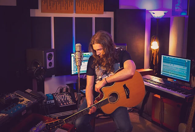 A musician in a recording studio, deeply focused on playing an acoustic guitar in Central Oregon.