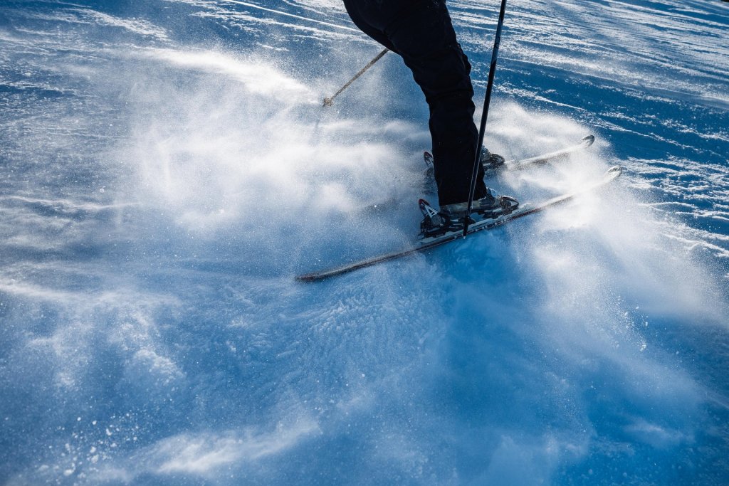 A skier in black gear gracefully glides down a snowy slope, leaving a trail of snow in their wake in Central Oregon.
