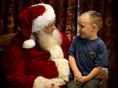 Santa Claus sits with a young boy, both smiling and engaged in conversation in Central Oregon.