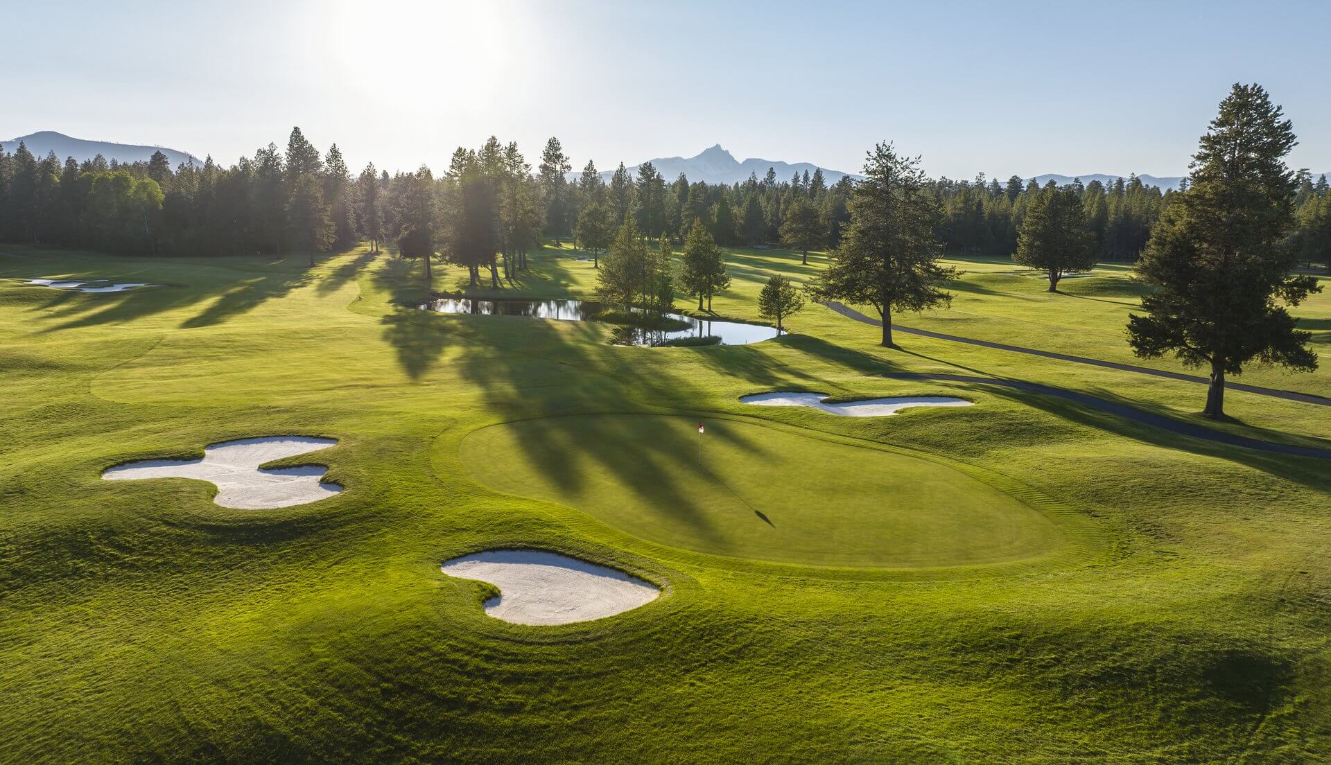 Sunlight gleams in the distance over a forested horizon at Big Meadow golf course at Black Butte Ranch in Sisters, Oregon.