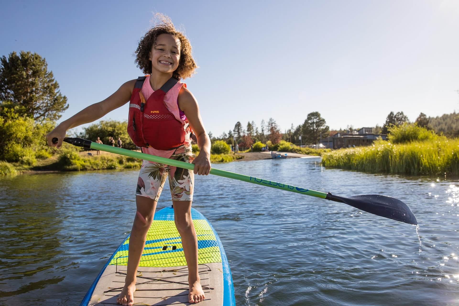 Child paddle boards near sunriver oregon with a smile