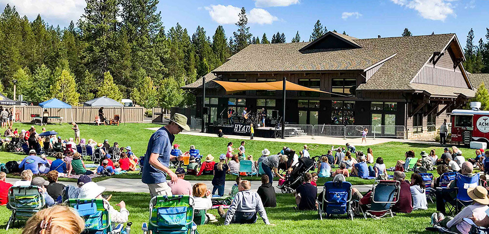 A lively outdoor concert with a large crowd enjoying music and food at a scenic venue in Central Oregon.