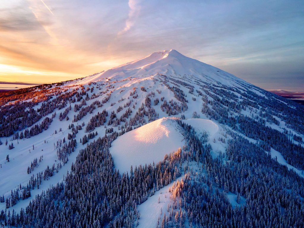 An overhead view of the snow- and tree-covered peaks at Mt. Bachelor at sunset.