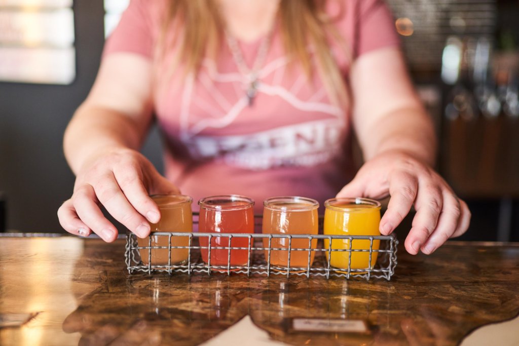 A woman serving colorful drinks from a tray at a bar in Central Oregon.