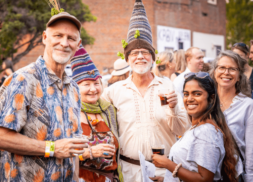 A group of people at a festival, wearing colorful hats and enjoying drinks in Central Oregon.
