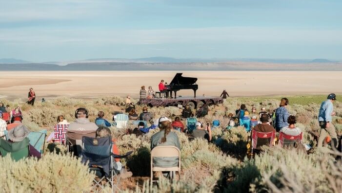 A grand piano performance on a sandy stage, surrounded by a vast desert landscape in Central Oregon.