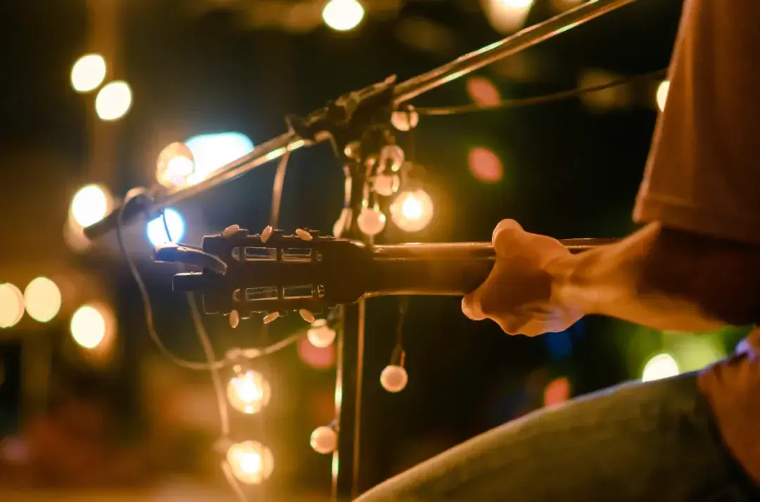A musician strums a guitar under twinkling lights, creating a cozy ambiance in Central Oregon.