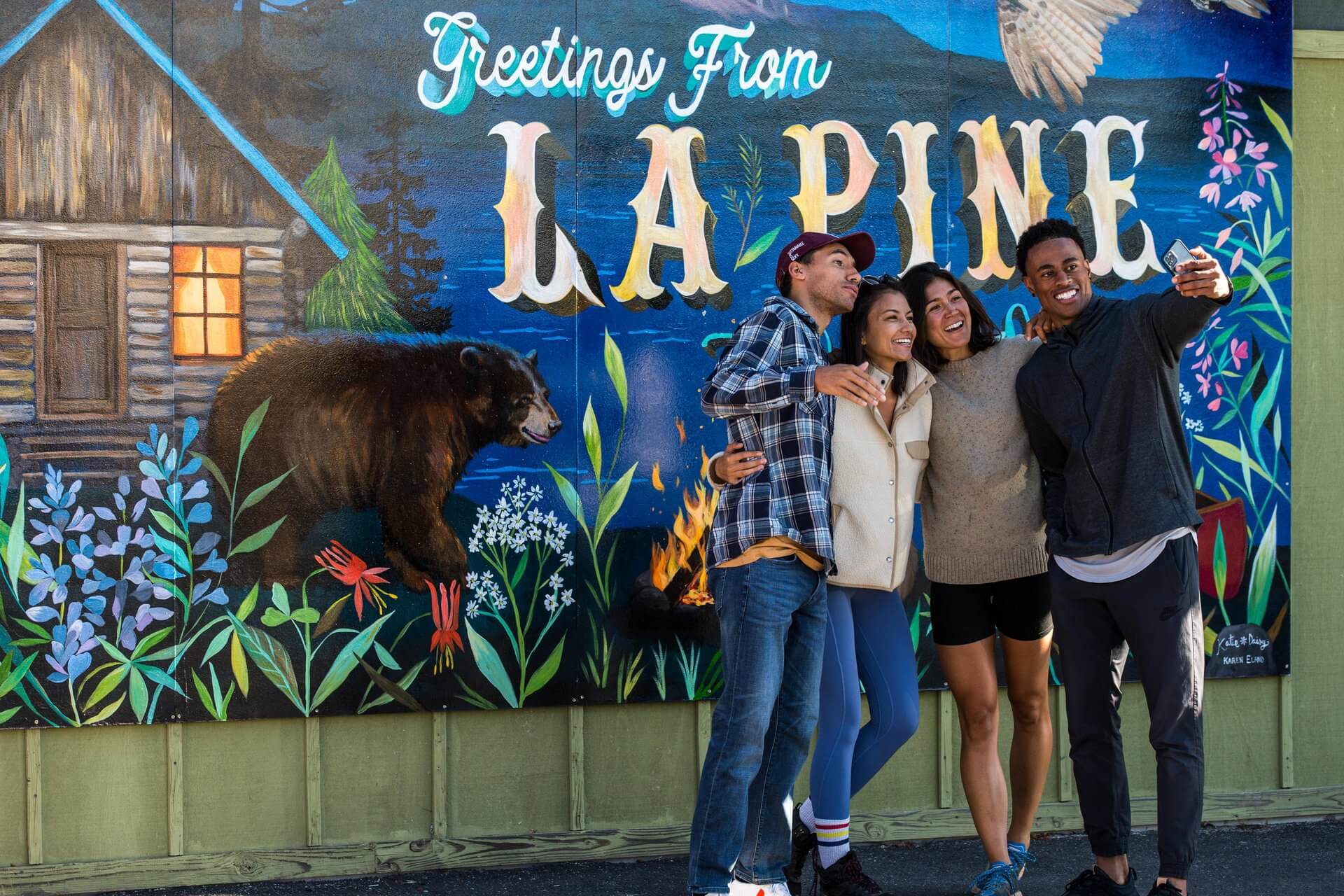 Three friends taking a selfie in front of a vibrant mural in La Pine in Central Oregon.
